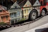 A chain hangs in front of the side of a bus with a row of houses painted on it